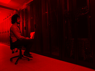 Image showing engineer working on a laptop in server room