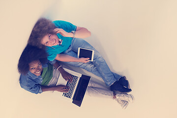 Image showing multiethnic couple sitting on the floor with a laptop and tablet