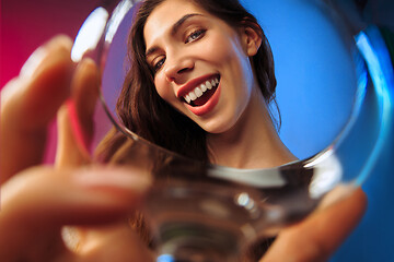 Image showing The surprised young woman in party clothes posing with glass of wine.