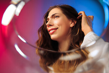 Image showing The surprised young woman in party clothes posing with glass of wine.