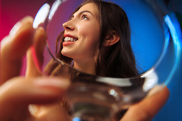 Image showing The surprised young woman in party clothes posing with glass of wine.