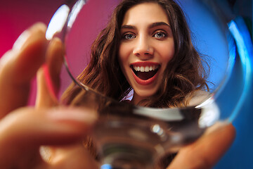 Image showing The surprised young woman in party clothes posing with glass of wine.