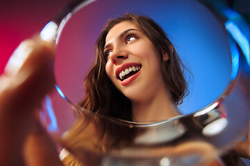 Image showing The surprised young woman in party clothes posing with glass of wine.