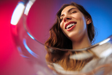 Image showing The surprised young woman in party clothes posing with glass of wine.