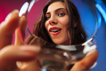 Image showing The surprised young woman in party clothes posing with glass of wine.