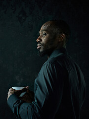 Image showing Stylish young black man with cup of coffee posing on dark background.