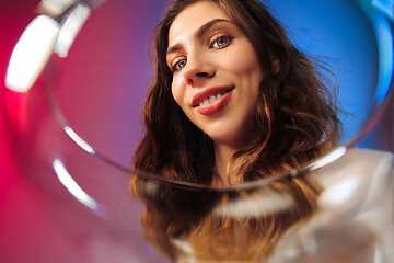 Image showing The surprised young woman in party clothes posing with glass of wine.