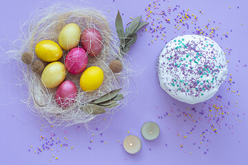 Image showing Easter eggs in the nest, cake, candles on a purple background