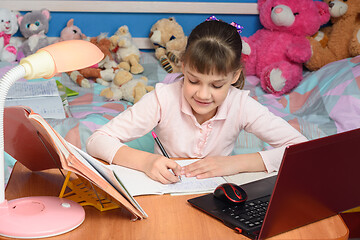 Image showing in the children\'s room sits a girl at a desk and makes a homemade