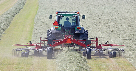 Image showing Tractor and grass turner work in dutch meadow