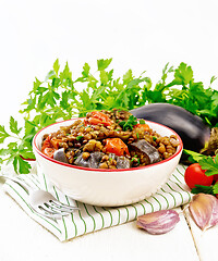 Image showing Lentils with eggplant in bowl on wooden board