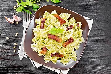 Image showing Farfalle with pesto and bacon on dark board top