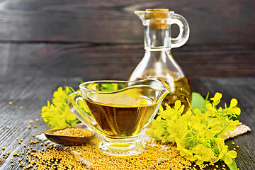 Image showing Oil mustard in gravy boat and decanter on dark board