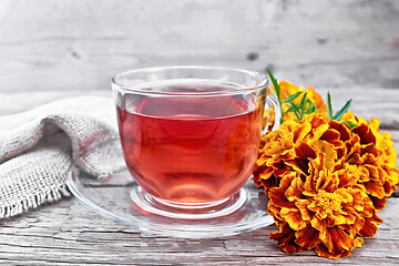 Image showing Tea herbal of marigolds in glass cup on wooden board