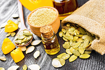 Image showing Oil pumpkin in vial with flour on dark wooden board