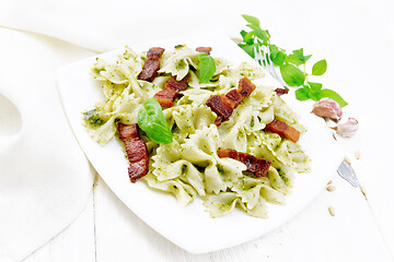 Image showing Farfalle with pesto and bacon in plate on board