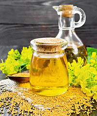 Image showing Oil mustard in jar and decanter with flower on burlap