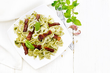 Image showing Farfalle with pesto and bacon in plate on light board top