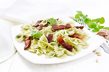 Image showing Farfalle with pesto and bacon in plate on white board