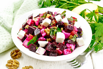 Image showing Salad with beetroot and walnuts in plate on light board