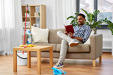 Image showing man reading book and resting after home cleaning