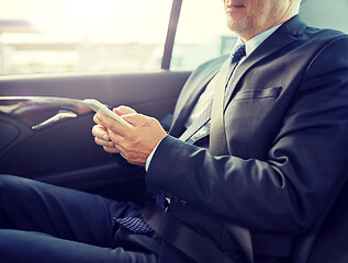 Image showing senior businessman texting on smartphone in car