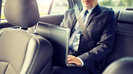 Image showing senior businessman with laptop driving in car