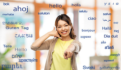 Image showing woman making phone call gesture over foreign words