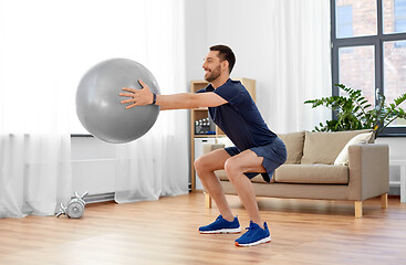 Image showing man exercising and doing squats with ball at home