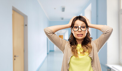 Image showing stressed female student holding to head at school