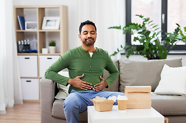 Image showing pleased indian man eating takeaway food at home