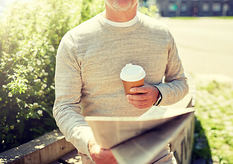 Image showing senior man with coffee reading newspaper outdoors