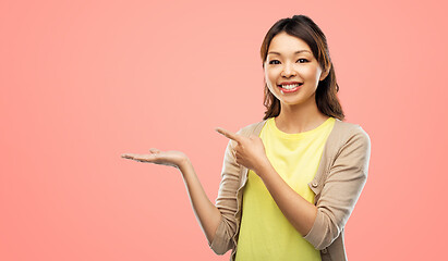 Image showing happy asian woman holding something on hand