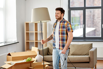 Image showing happy man with floor lamp moving to new home