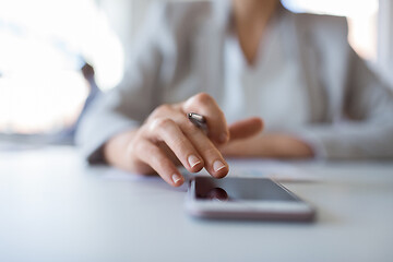 Image showing hand of businesswoman using smartphone at office