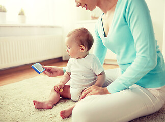 Image showing happy mother showing smartphone to baby at home