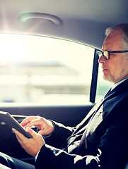 Image showing senior businessman with tablet pc driving in car