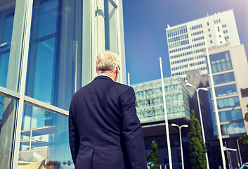 Image showing senior businessman walking along city street