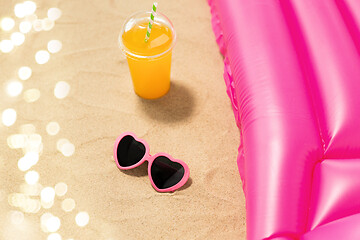 Image showing sunglasses, juice and pool mattress on beach sand