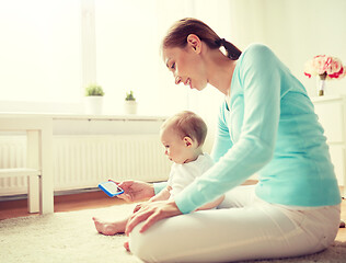 Image showing happy mother showing smartphone to baby at home