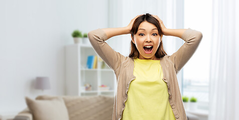 Image showing happy asian woman holding to her head at home