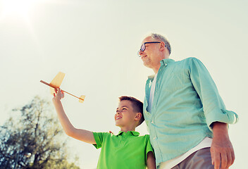 Image showing senior man and boy with toy airplane over sky