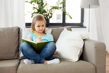 Image showing little girl with diary sitting on sofa at home