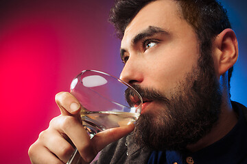 Image showing The surprised young man posing with glass of wine.