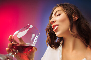 Image showing The surprised young woman in party clothes posing with glass of wine.