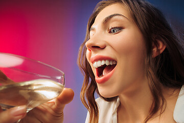 Image showing The surprised young woman in party clothes posing with glass of wine.