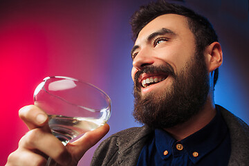 Image showing The surprised young man posing with glass of wine.