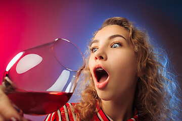 Image showing The surprised young woman in party clothes posing with glass of wine.