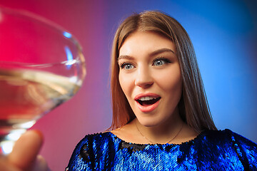 Image showing The surprised young woman in party clothes posing with glass of wine.