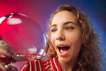 Image showing The surprised young woman in party clothes posing with glass of wine.